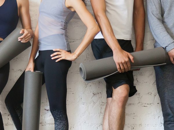 Yogagruppe mit zusammengerollten Matten